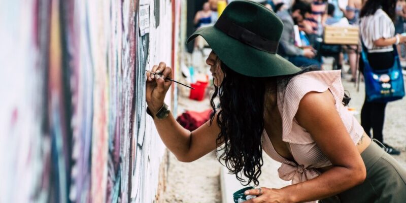 photo of woman painting on wall